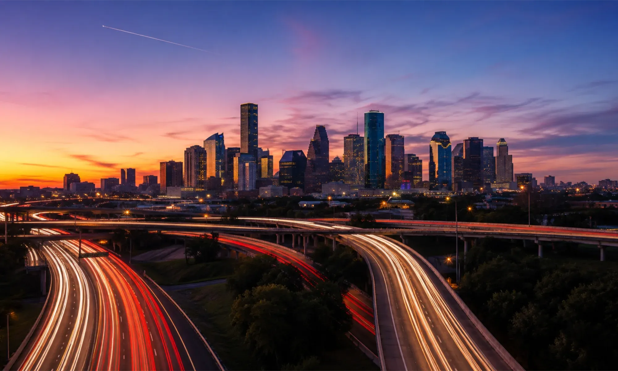 The Houston skyline at dusk with highway light trails in the foreground
